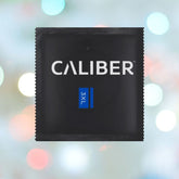 A black package featuring the "Caliber" brand with a blue "3XL" label sits against a soft-focus, colorful bokeh background.
